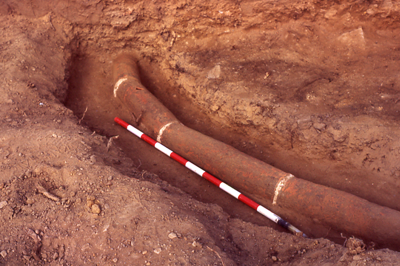 Tubería romana de cerámica parcialmente descubierta durante una excavación arqueológica.