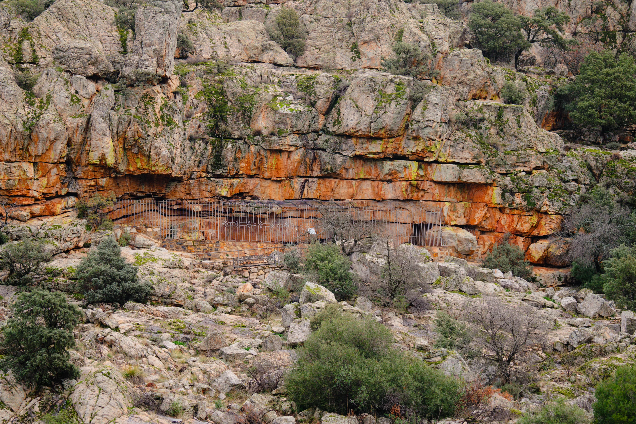 Vista del abrigo de Peña Escrita en Fuencaliente, con la reja de protección y su entorno rocoso.